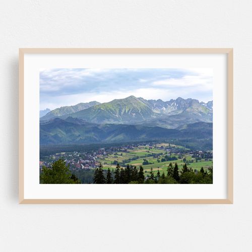 Picturesque view of the Tatra mountain range in southern Poland, lush green hills, huge large peaks, village houses, small towns farmlands, cloudy sky, natural landscape travel destinations concept