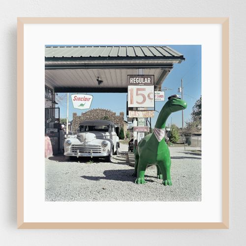 Vintage roadside stop on Route 66 with a quirky dinosaur and classic car