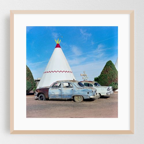 Vintage cars parked near a retro tepee motel along the nostalgic route 66 in blue skies