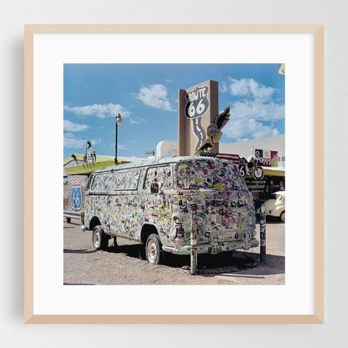 Vintage van adorned with stickers stands proudly along the iconic route 66 under a bright sky